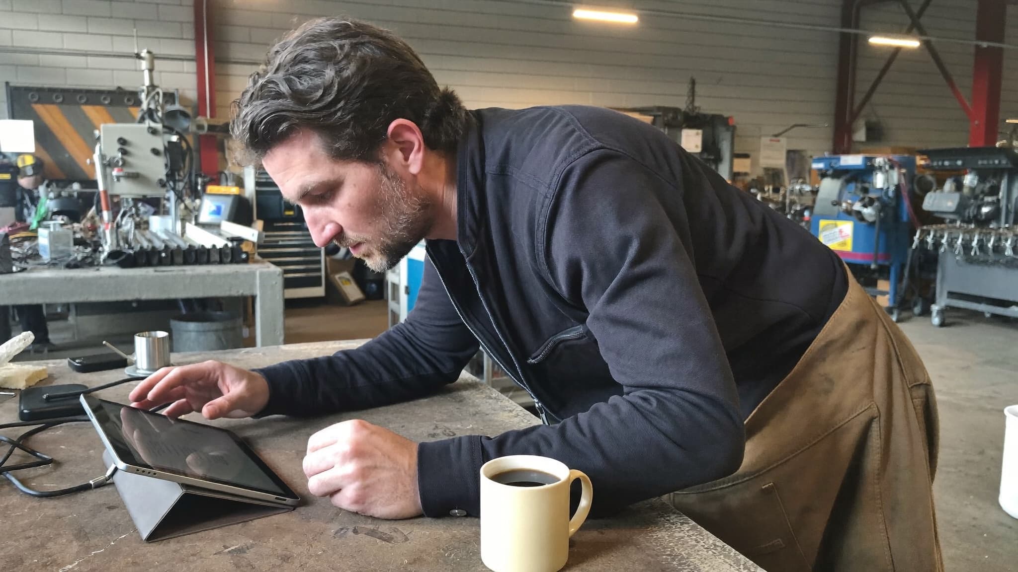 Betriebsinhaber prüft seine Zahlen auf dem Tablet in der Werkstatt